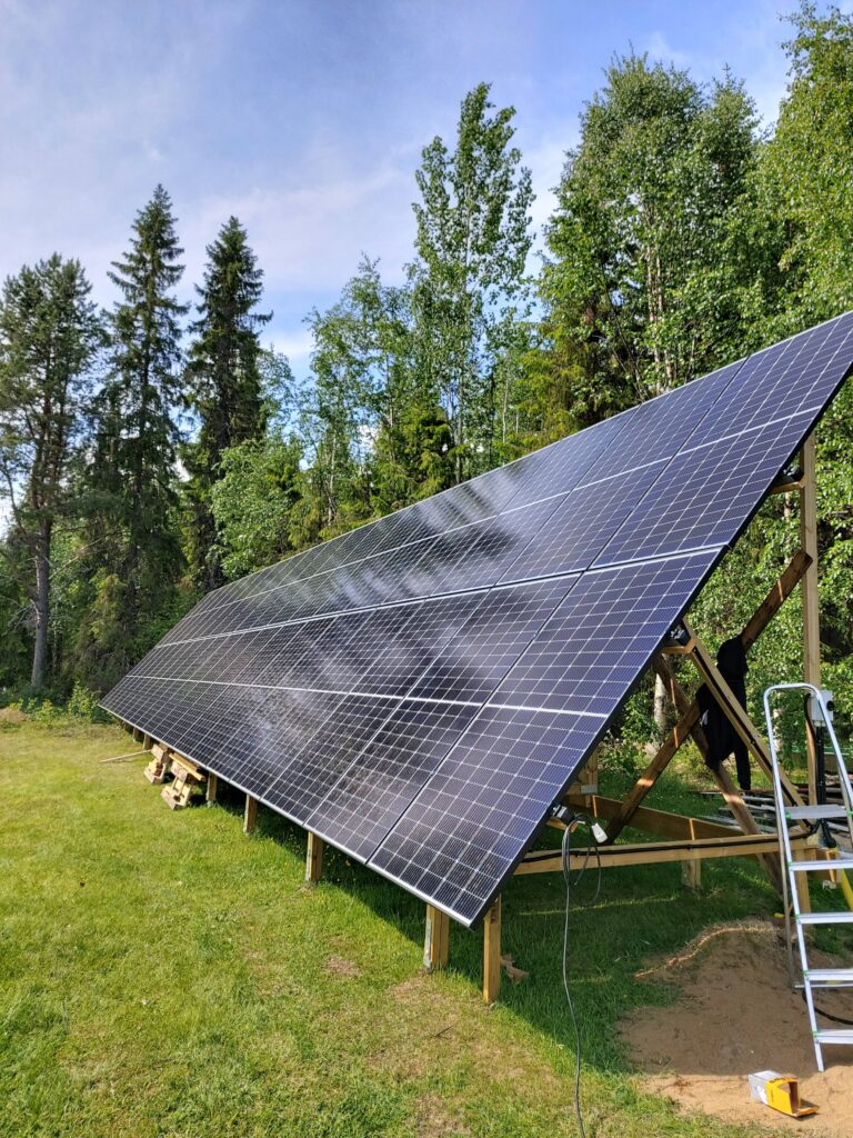 Ett stort solpanelssystem installerat utomhus omgiven av träd under en klarblå himmel.